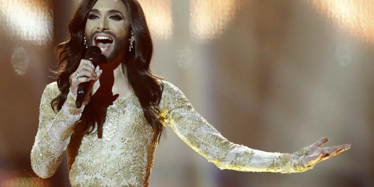 Conchita Wurst, zwyciężczyni Eurowizji, w złotej sukni z cekinami śpiewa na scenie.