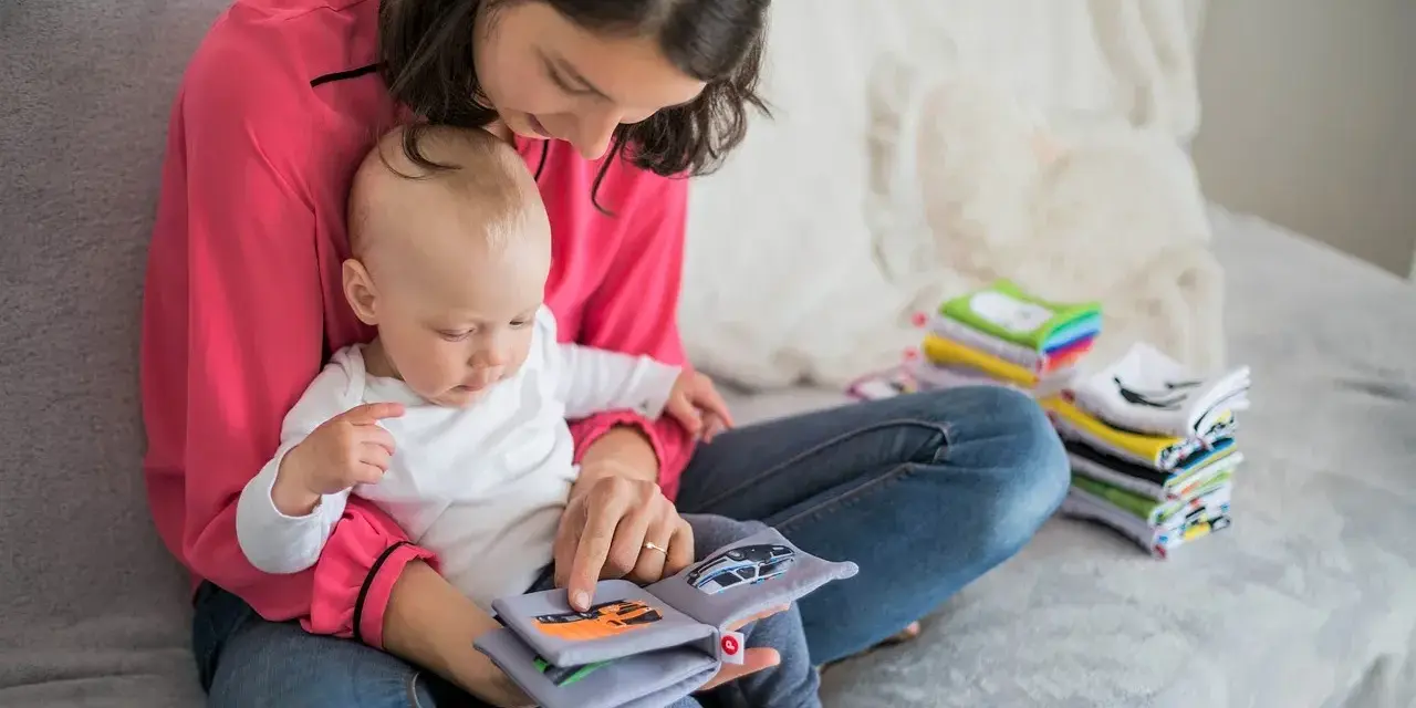 Mama czyta dziecku książeczkę o samochodach. Wycofane dziecko, przyczyny jego nieśmiałości mogą być różne, ale wspólne czytanie buduje więź.