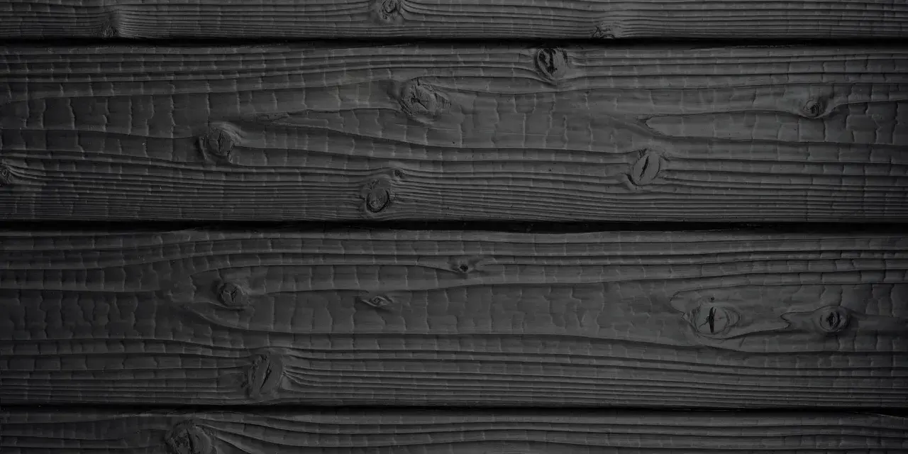 Tavolato scuro, con venature evidenti e nodi che emergono dal **legno bruciato**.
