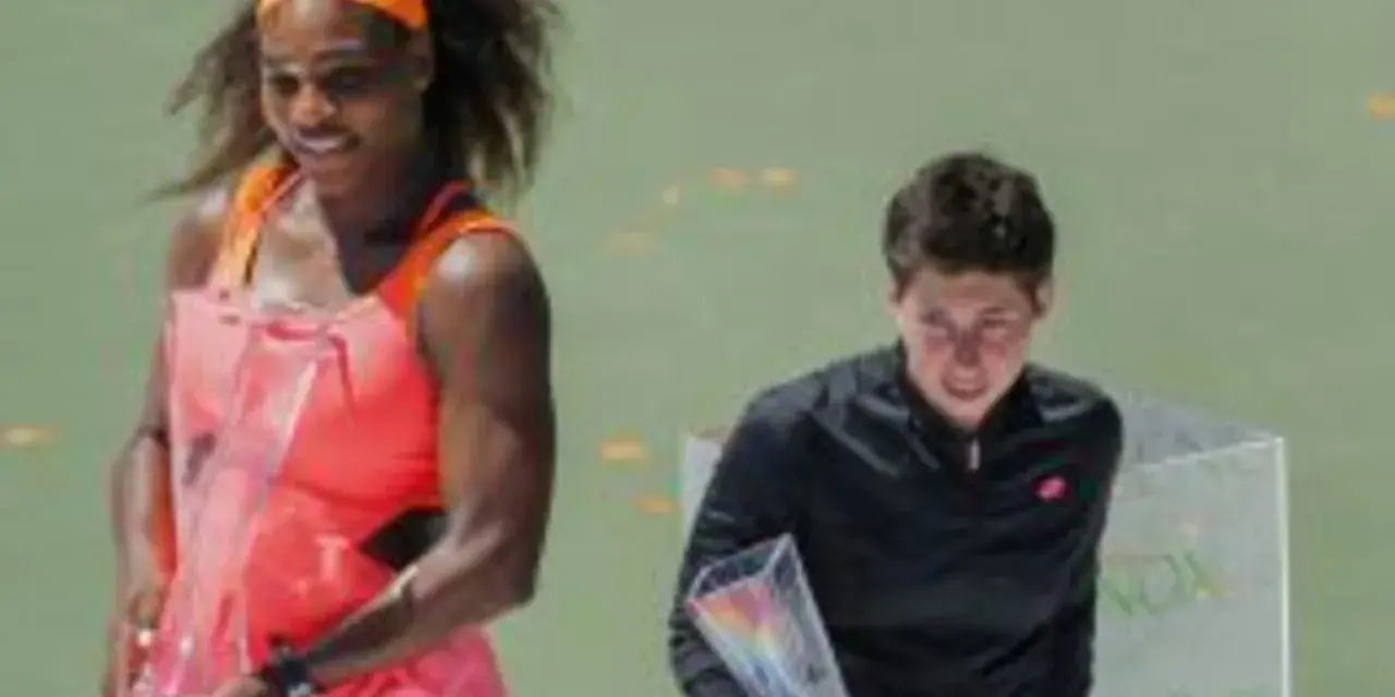 Serena Williams, con su impresionante altura, celebra con un trofeo. A su lado, otra tenista recibe su premio.