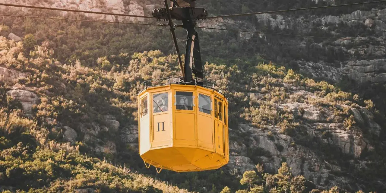 A yellow cable car ascends the rugged slopes of Montserrat.