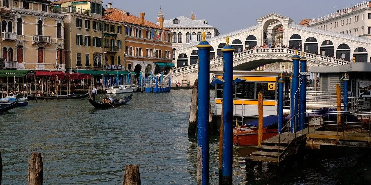 Venice canal with gondola, Rialto Bridge, and buildings.