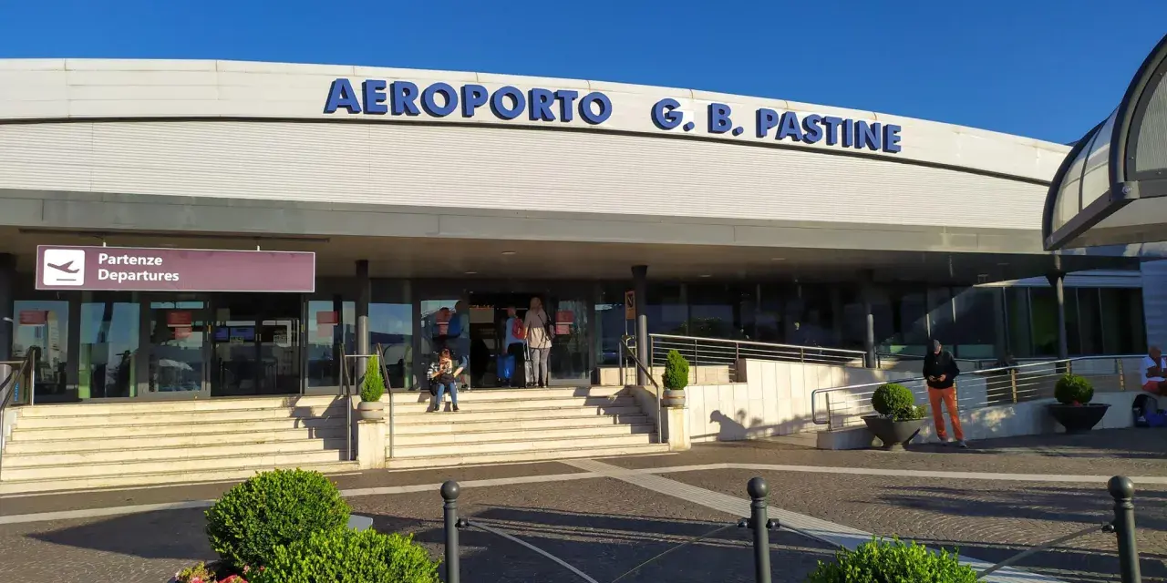 Wejście do Aeroportu G.B. Pastine w Rzymie Ciampino. Słoneczny dzień, ludzie czekają na odloty.