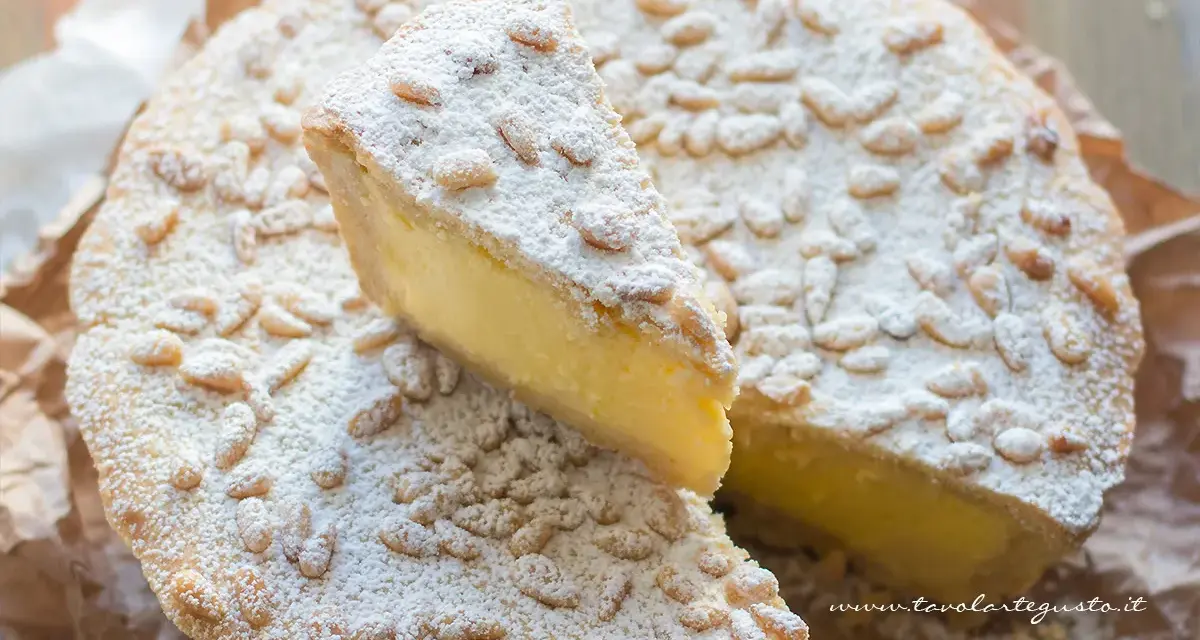 Una fetta di torta della nonna, ricca di crema e cosparsa di pinoli e zucchero a velo, pronta per essere gustata.