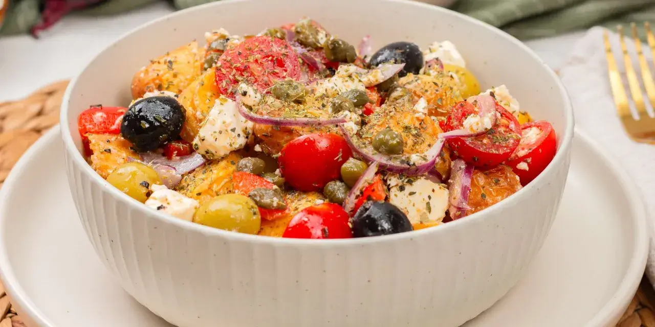 Ein bunter Kartoffelsalat mal anders: mit Feta, Tomaten, Oliven und Kapern, appetitlich gewürzt.