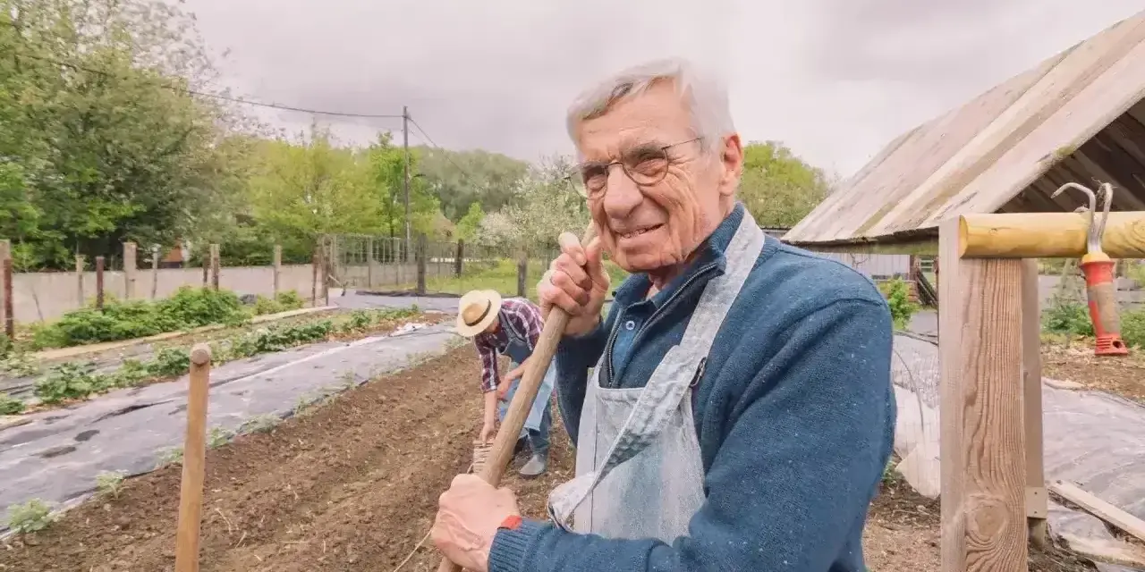 Uśmiechnięty starszy pan z łopatą w ręku, pracujący w ogrodzie. Zastanawia się, jaka emerytura z KRUS po 10 latach będzie mu przysługiwać.