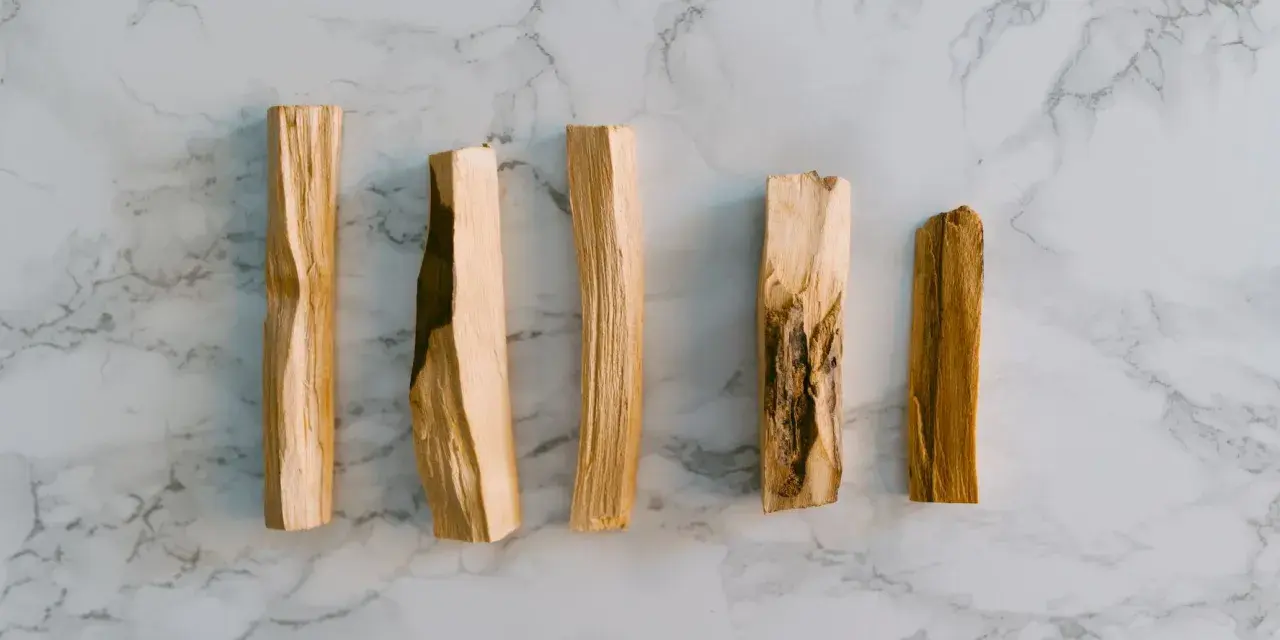 Seis trozos de palo santo sobre mármol. El palo santo se usa para purificar y aromatizar.