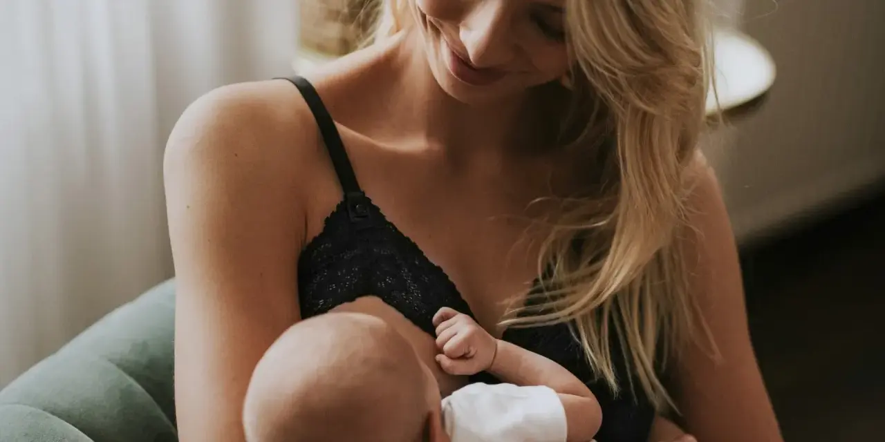 Uśmiechnięta mama karmi piersią swoje dziecko. Delikatne chwile bliskości i miłości.