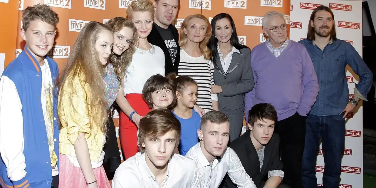 Rodzinka.pl obsada: młodzi aktorzy i starsze pokolenie pozują do wspólnego zdjęcia na tle ścianki z logo serialu.