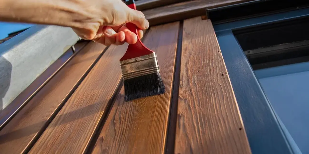 Application d'une couche protectrice sur des lattes de bois avec une peinture à l'huile sur bois technique.
