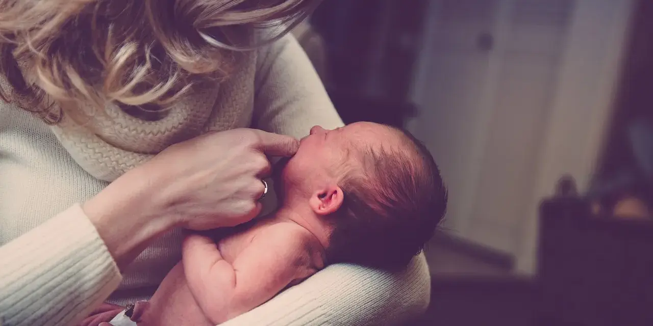 Delikatne dotknięcie palcem ust noworodka, gdy mama próbuje poradzić sobie z kryzysem laktacyjnym.