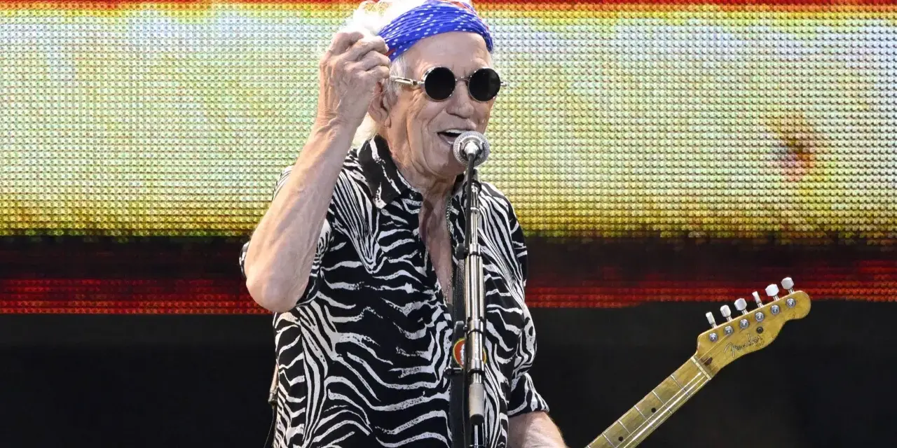 Keith Richards heute, mit blauem Bandana und Sonnenbrille, spielt Gitarre auf der Bühne.