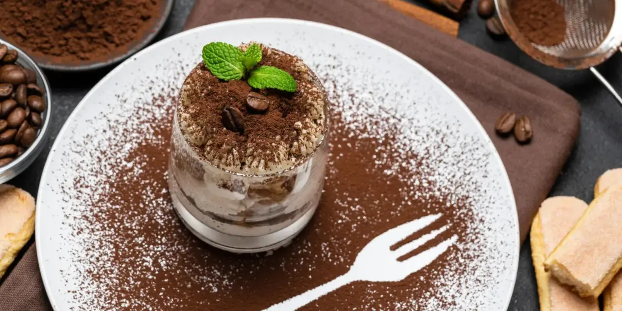 Pyszne tiramisu w pucharku, posypane kakao i kawą. Idealne desery co zamiast surowych jaj, z miętą i biszkoptami.