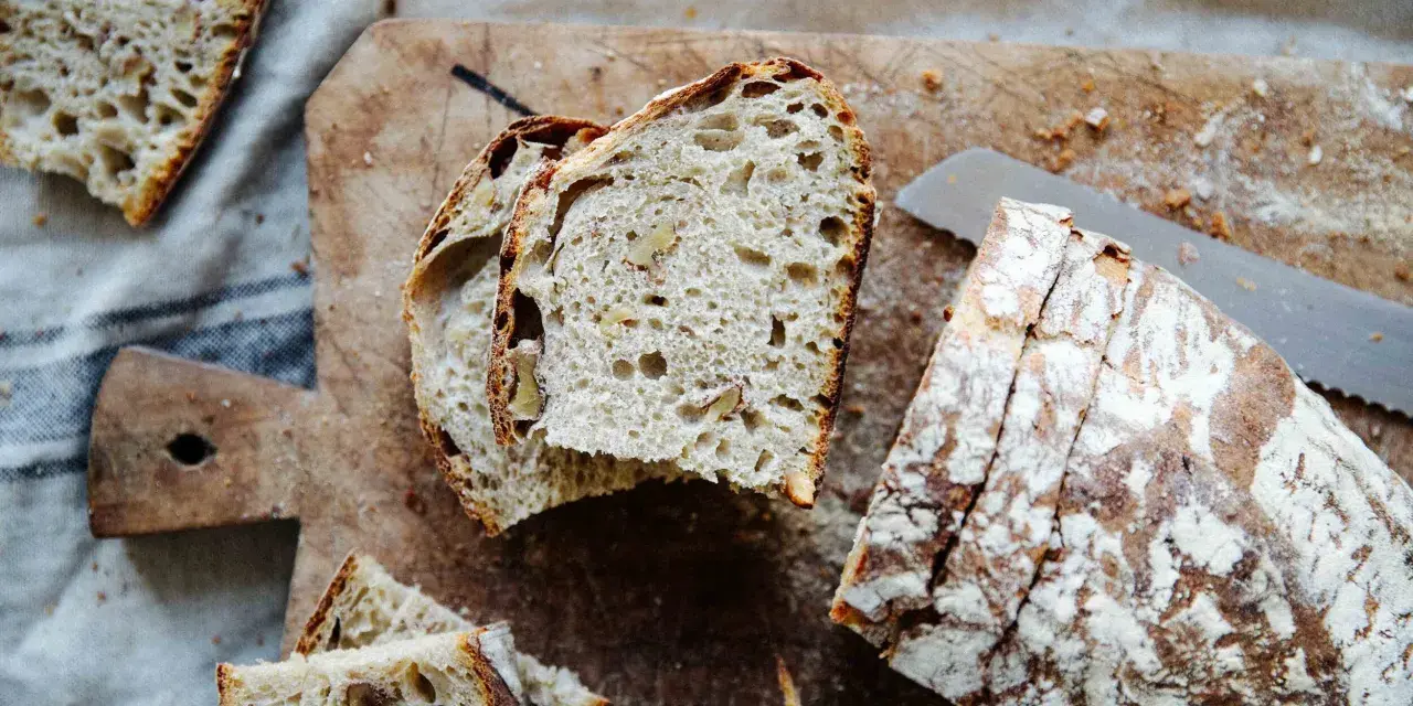 Frisches Brot mit Nüssen, perfekt **mit Dampf gebacken**, liegt auf einem Holzbrett.