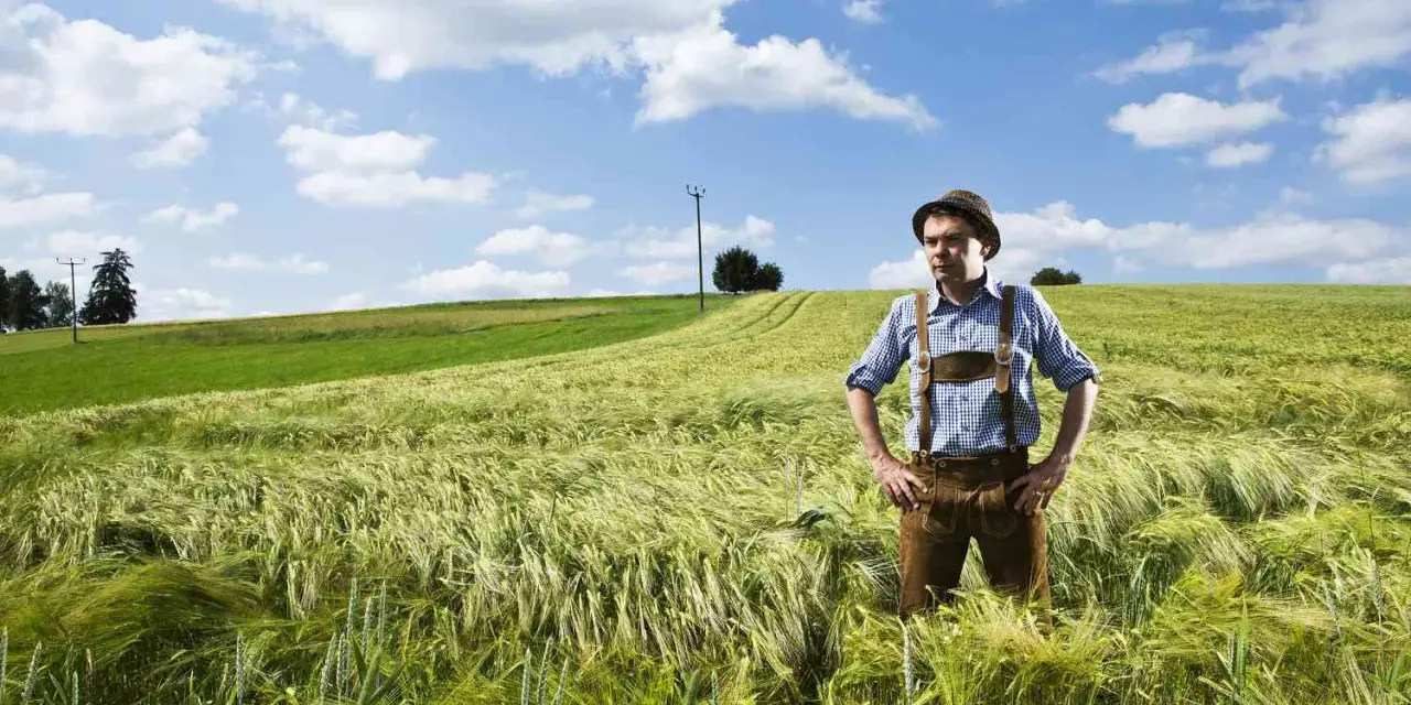 Un homme en culotte de peau et chapeau se tient dans un champ d'orge. Son nom, Hoffmann, pourrait avoir une origine juive, évoquant une histoire ancestrale.