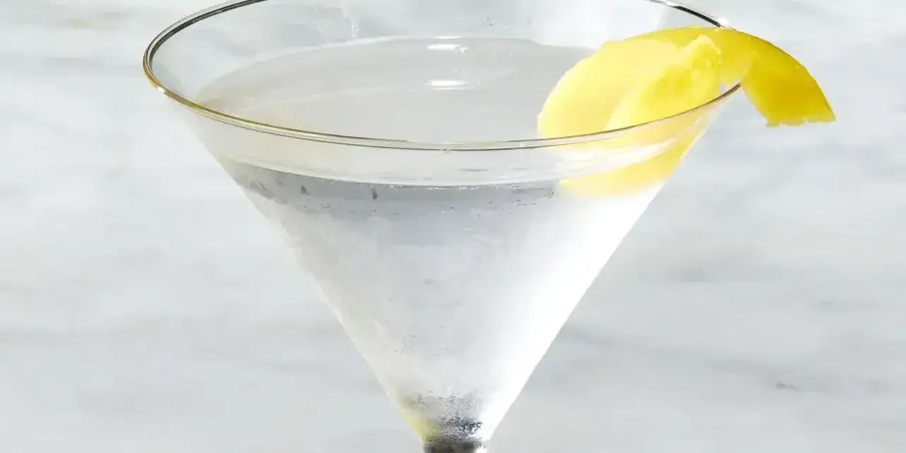Chłodny martini z ginem, ozdobiony skórką cytryny, czeka na degustację.