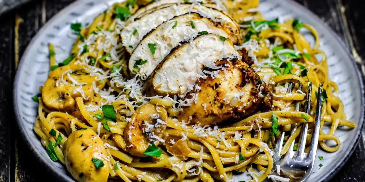 Cremiges Chicken Alfredo mit Pilzen, garniert mit Parmesan und Petersilie. Ein köstliches Gericht, das Lust auf mehr macht.