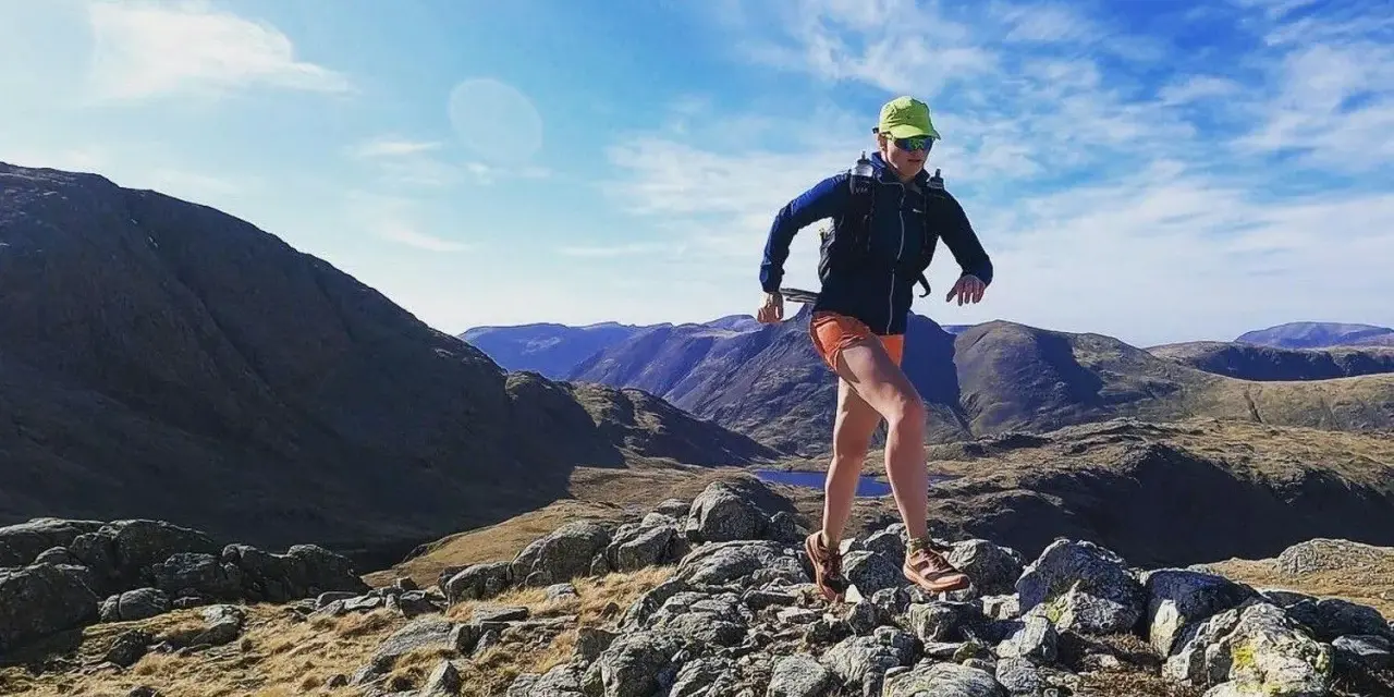 Atleta corre su sentiero roccioso in montagna. Il fast hiking significato è correre in montagna con attrezzatura leggera.