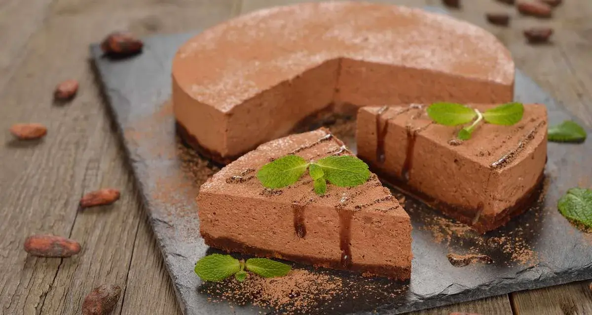 Deliziosa bavarese al cioccolato, spolverata di cacao e decorata con menta fresca. Due fette sono già pronte per essere gustate.