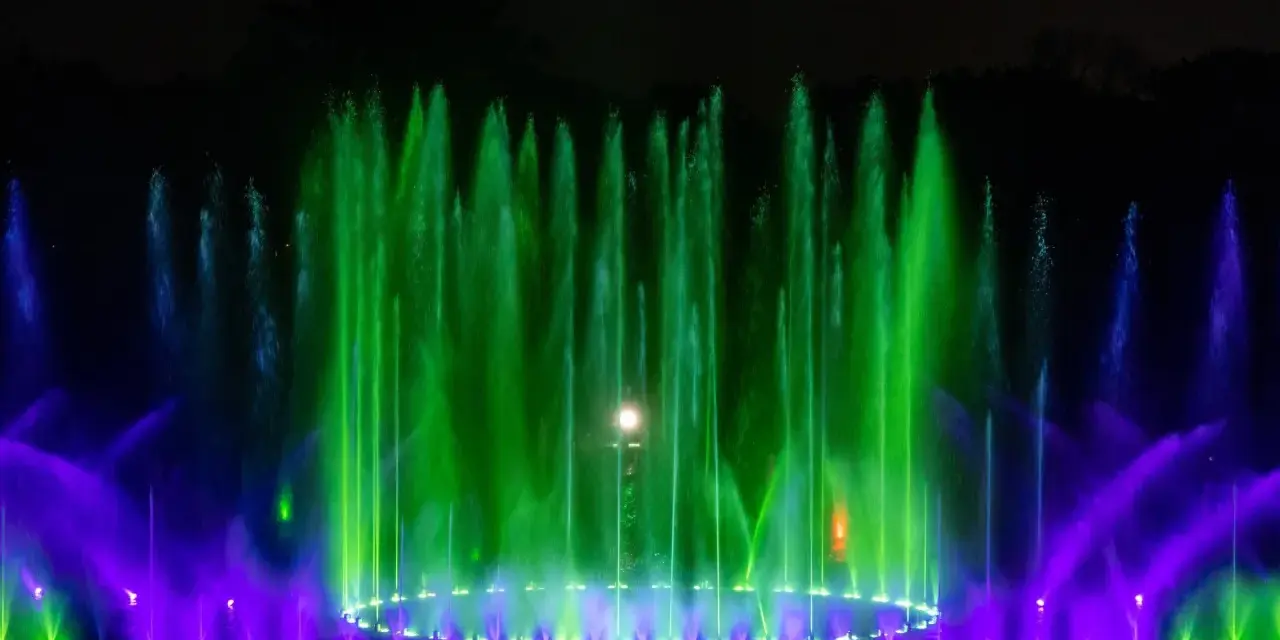 Spektakularna fontanna multimedialna we Wrocławiu nocą, tańczące strumienie wody w zielonych i fioletowych barwach tworzą magiczny pokaz.