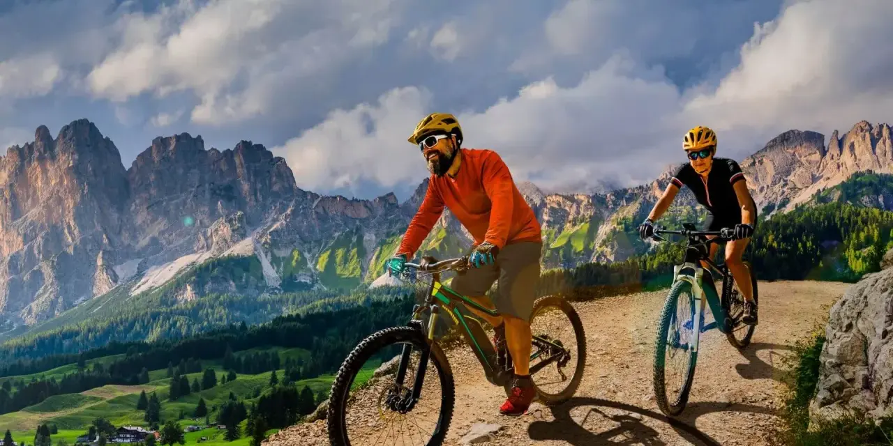 Due ciclisti si godono uno sport di montagna su sentieri sterrati con maestose vette sullo sfondo.