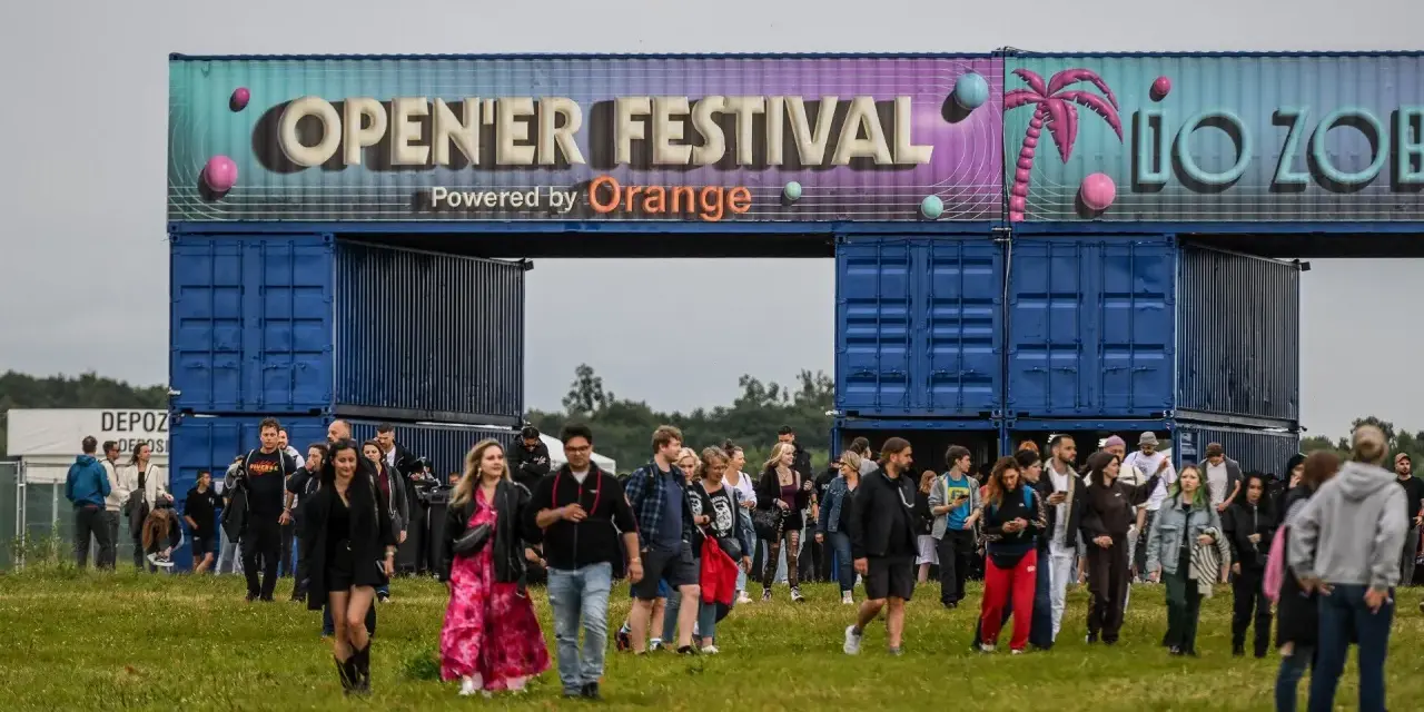 Tłum ludzi wchodzi na teren festiwalu. Nad nimi brama z napisem "OPEN'ER FESTIVAL". Kto będzie następny?
