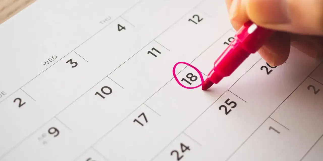 Une main entoure le 18 sur un calendrier, marquant le début des vacances scolaires à Fribourg.