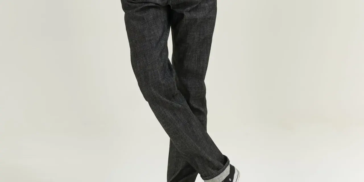 Uomo con jeans scuri e sneakers, che incarnano il comfort fit significato di libertà di movimento e stile casual.