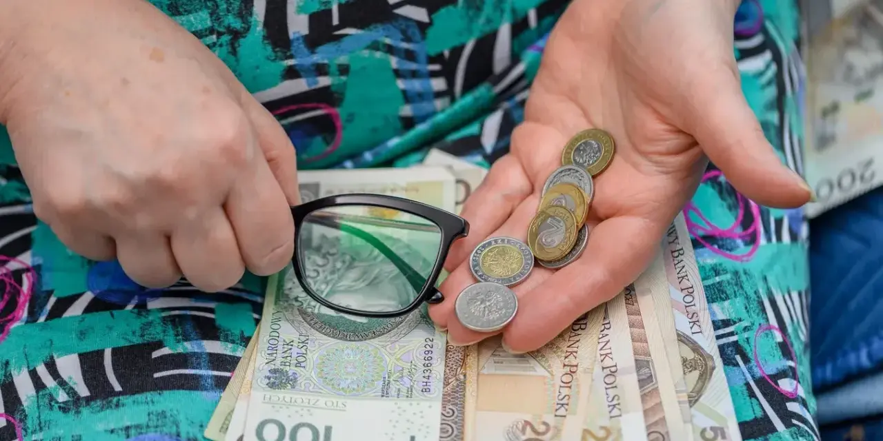 Dłonie trzymające okulary, monety i polskie banknoty.