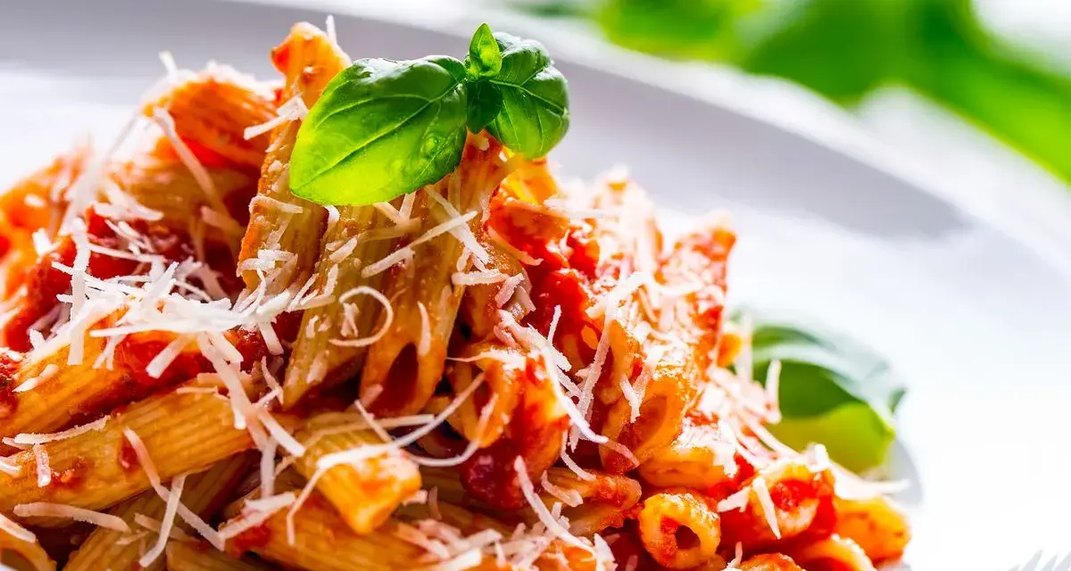 Penne al pomodoro con basilico fresco e parmigiano grattugiato, un classico tra i sughi per pasta.