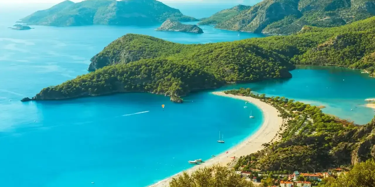 Turcja zachwyca turkusowym morzem i zielonymi wzgórzami. Widok na zatokę z plażą i górami.