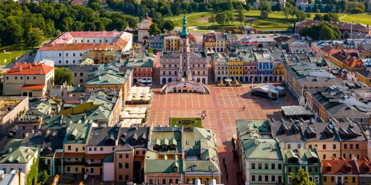 Zamość miasto idealne: renesansowy rynek z kolorowymi kamienicami i ratuszem, otoczony zielenią.