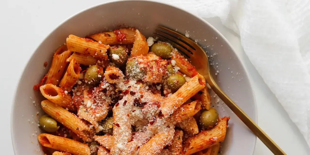 Penne z sosem pomidorowym, oliwkami i startą mozzarellą, posypane płatkami chili. Idealny makaron z mozzarellą na szybki obiad.