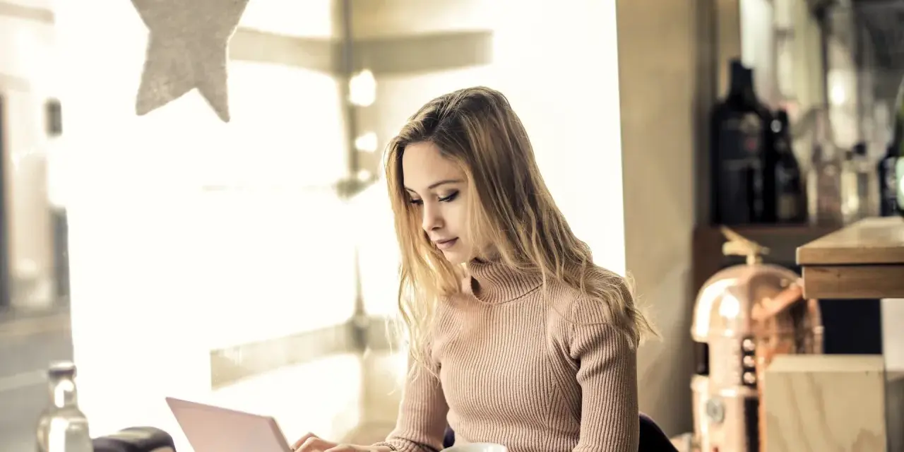 Kvinna skriver tack mail efter intervju på sin laptop vid ett bord med en tekanna.