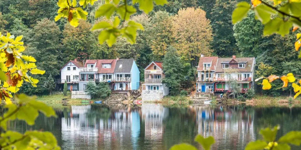 Malownicze domy nad jeziorem, idealne na jednodniowe wycieczki z Wrocławia. Jesienne liście dodają uroku.