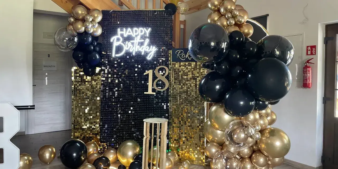 Elegancka ścianka do zdjęć na 18 urodziny z napisem "Happy Birthday" i liczbą 18, ozdobiona złotymi i czarnymi balonami.