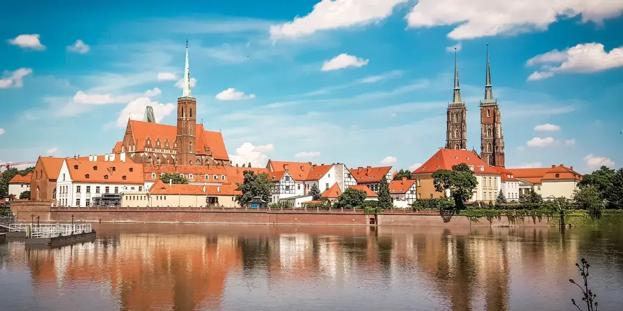Wrocławskie Ostrów Tumski z katedrą i kościołami, odbijające się w wodzie. W tle widać budynki, które mogłyby pomieścić muzeum sztuki mieszczańskiej.