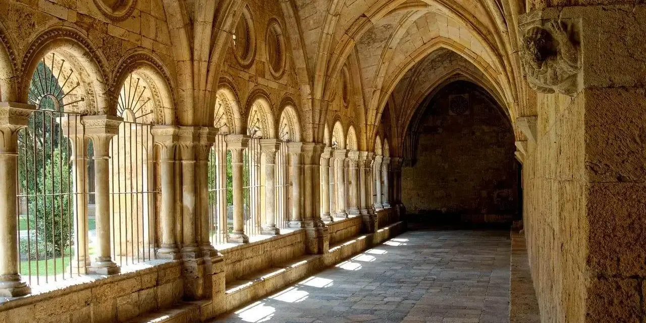Sunlight streams through arched cloisters, hinting at the diverse types of monasteries and their serene courtyards.