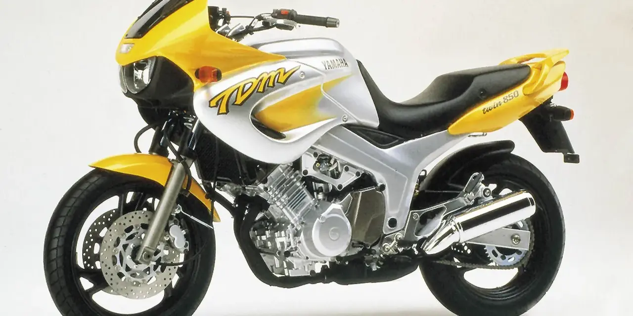 Żółto-srebrny motocykl Yamaha TDM 850 z charakterystycznym napisem "TDM" na baku. Gotowy na przygodę!