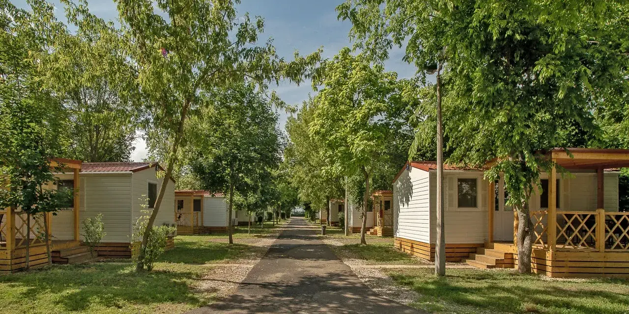 Alejka na hajdu camping, otoczona drzewami i białymi domkami z werandami.