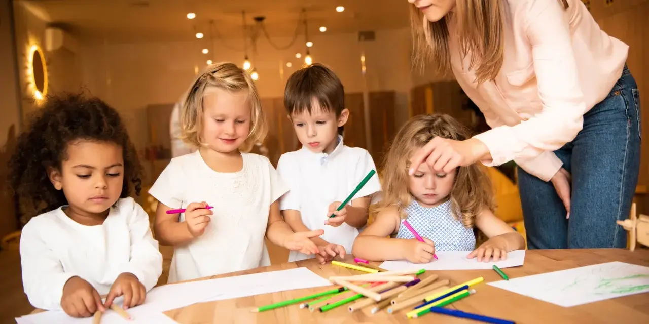 Nauczycielka wspiera dzieci w kreatywnym rysowaniu, promując edukację alternatywną.