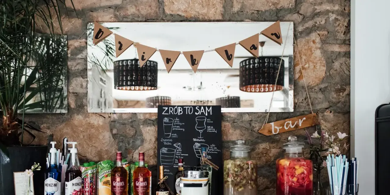 Stół z butelkami alkoholu, sokami i dzbankami z owocami, gotowy na drinki na wesele.