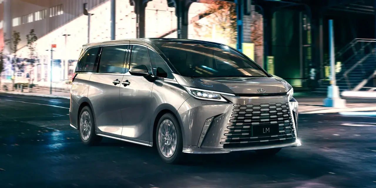 Srebrny van Lexus LM 350h na nocnej ulicy z rozmytym tłem.