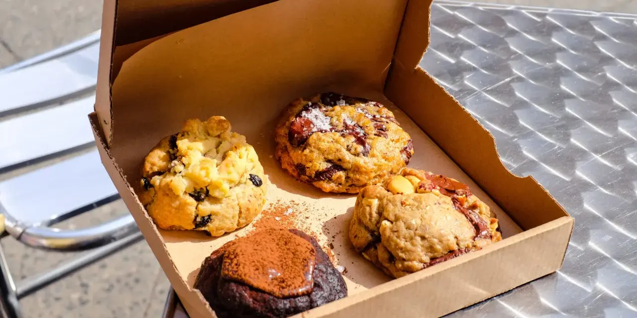 Vier köstliche, hausgemachte Cookies in einer Pappschachtel – die besten Cookies Berlins, bereit zum Genießen.