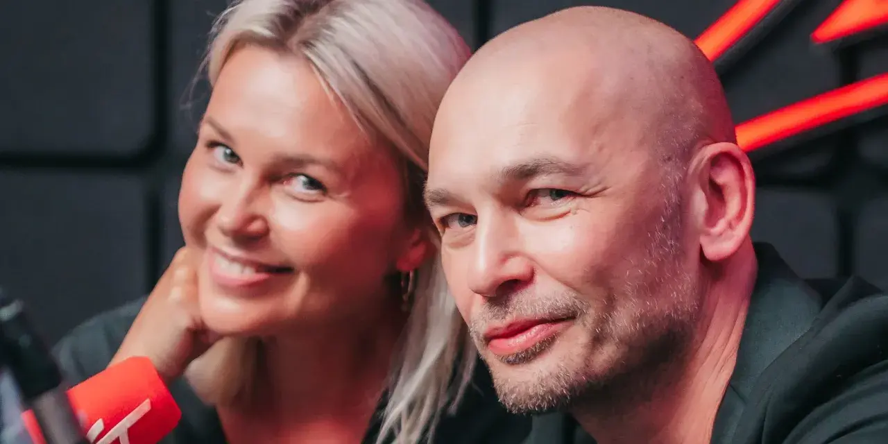 Tomasz Wygoda z żoną i dziećmi, uśmiechnięci przed mikrofonem.