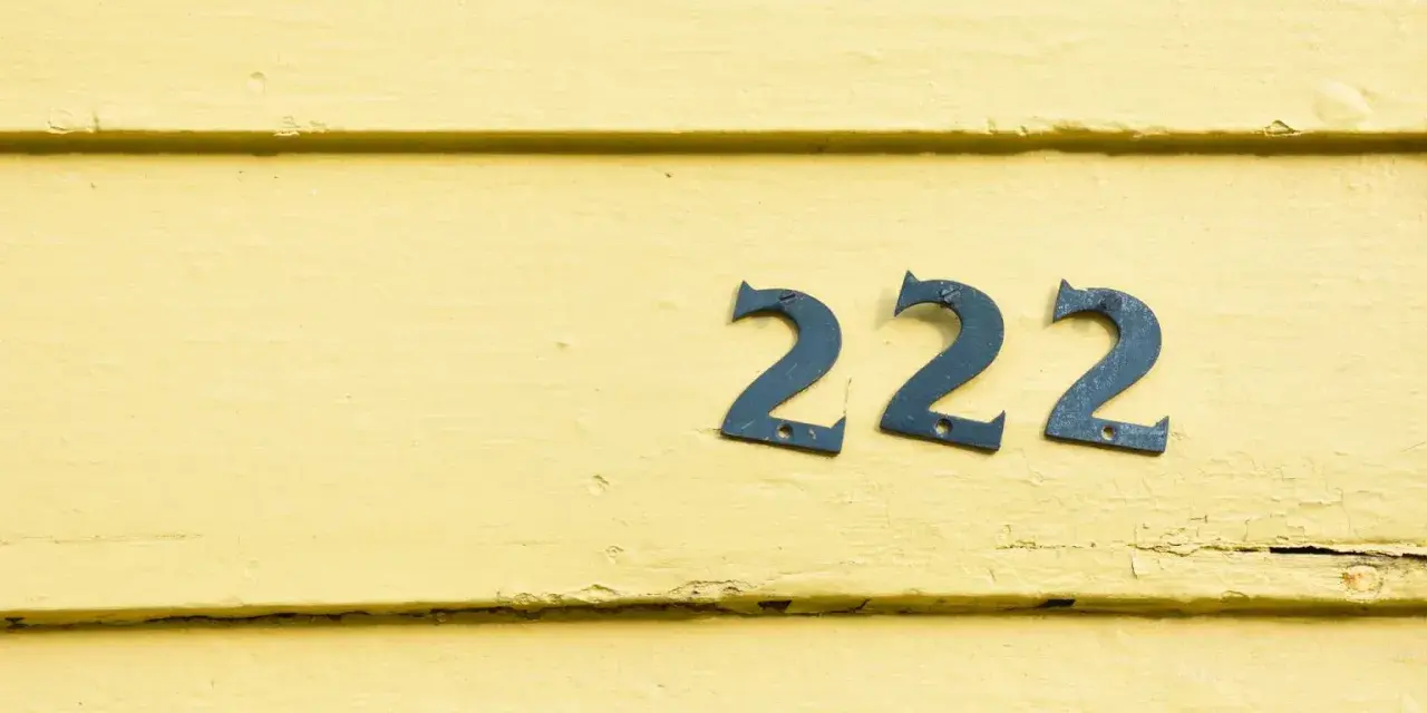 Na żółtej, drewnianej ścianie widnieje anielska liczba 222.
