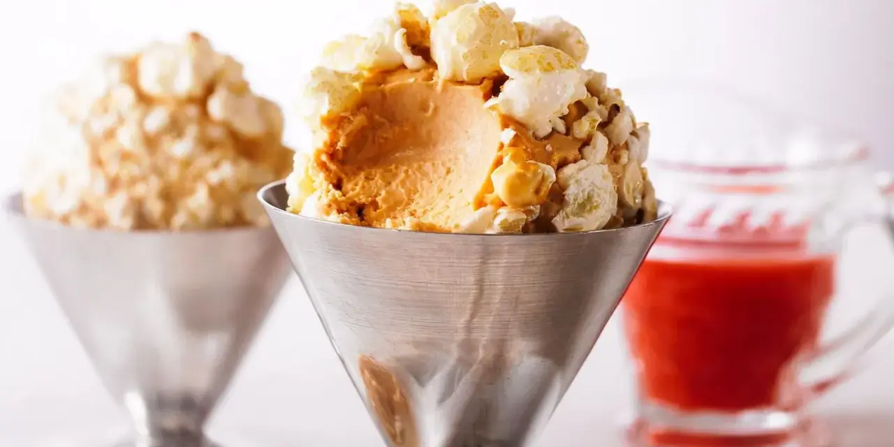 Cremiges Karamell-Popcorn-Eis in einem Metallbecher, garniert mit knusprigem Popcorn. Ein süßer Genuss!