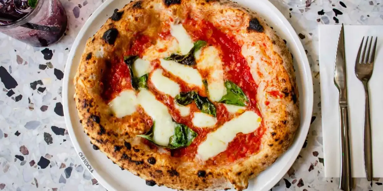 Pizza Margherita: darauf sind Tomatensauce, Mozzarella und frische Basilikumblätter.