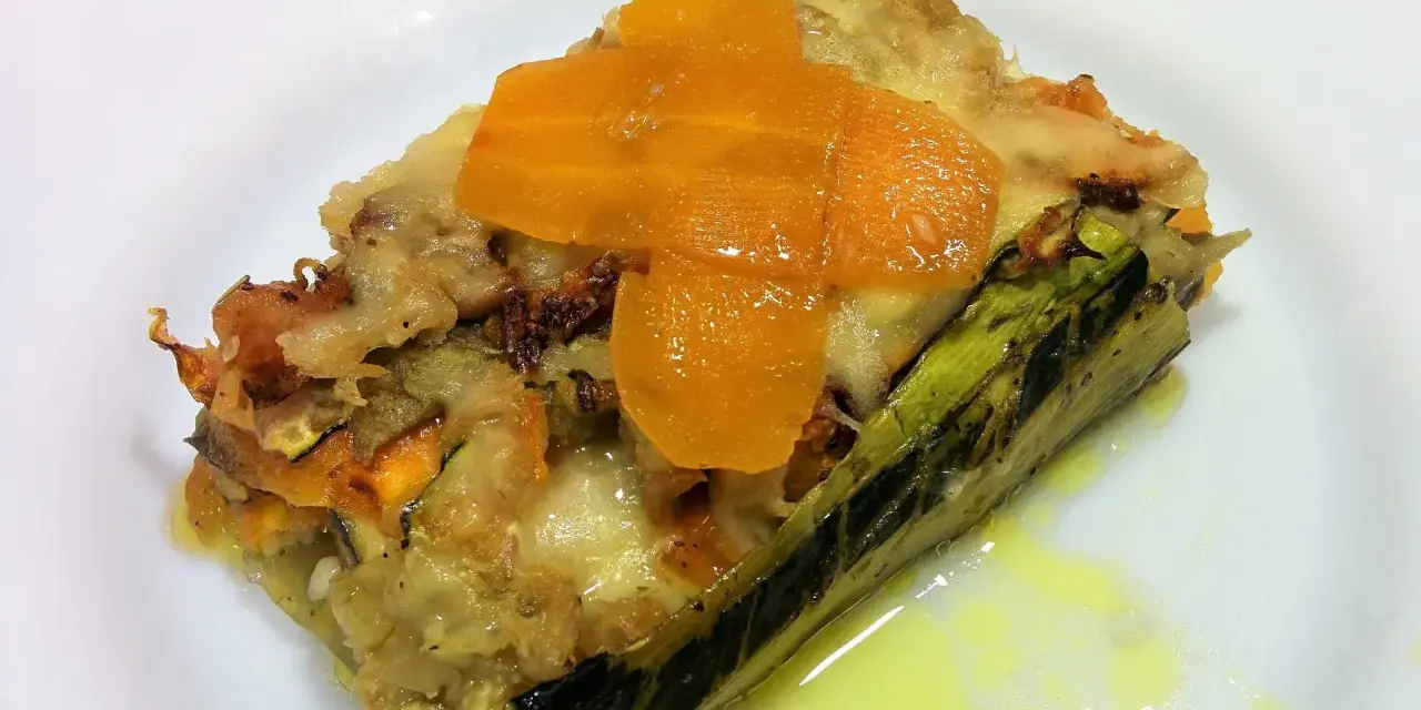 Deliciosa lasaña de verduras sin pasta, con capas de calabacín, zanahoria y queso fundido, servida en un plato blanco.