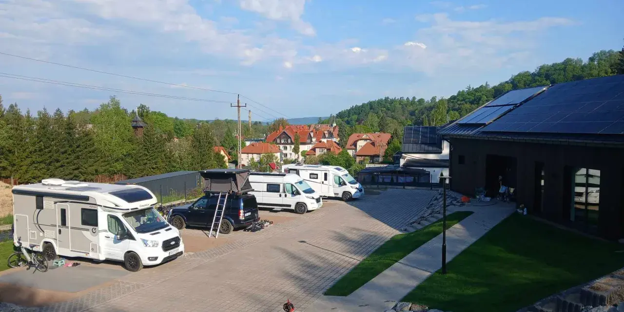 Kampery i samochody kempingowe zaparkowane na placu, gotowe na przygodę w Kudowie-Zdroju.